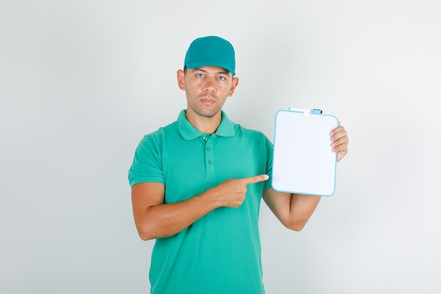 Levering man in groen t-shirt en pet wijzende vinger op bord