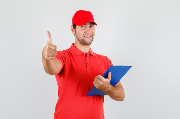 Levering man in rood t-shirt, pet klembord met duim omhoog houden en er vrolijk uitzien