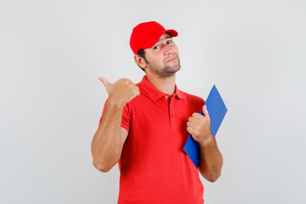Levering man in rood t-shirt, pet met klembord en duim opdagen