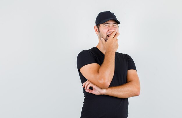 Levering man in zwart t-shirt, pet lachen met hand op mond