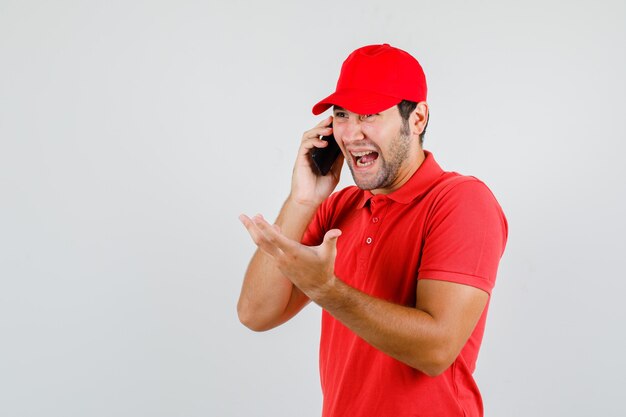 Levering man lachen terwijl praten over smartphone in rood t-shirt