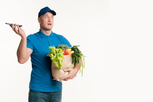 Levering man met telefoon en boodschappentas in handen