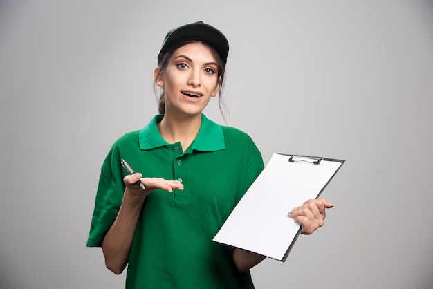 Levering vrouw in groen uniform klembord houden.