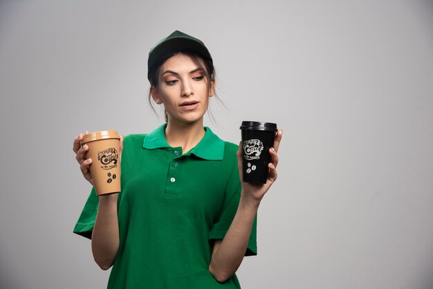 Levering vrouw in groene uniform poseren met heerlijke koffie.