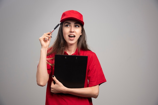 Levering vrouw in rood uniform klembord houden.