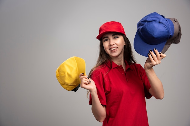 Levering vrouw in rood uniform met kleurrijke caps.