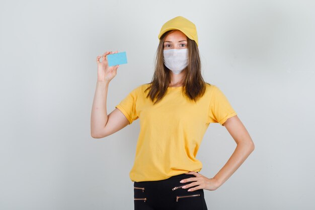 Levering vrouw met blauwe kaart in t-shirt, broek en pet, masker en op zoek blij