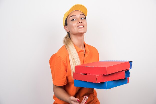 Levering vrouw met gele hoed met pizzadozen op witte ruimte