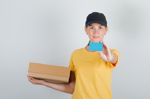 Levering vrouw met kartonnen doos en blauwe kaart in t-shirt en pet