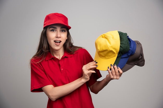 Levering vrouw met kleurrijke kappen poseren op grijze muur.