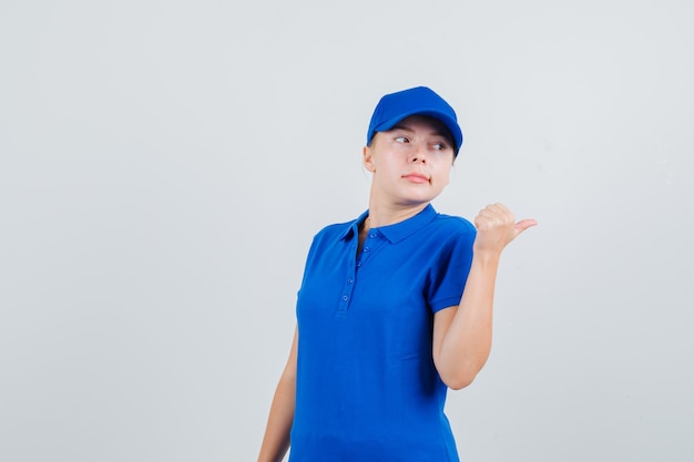 Levering vrouw wijzende duim weg in blauw t-shirt en pet en kijkt ontevreden