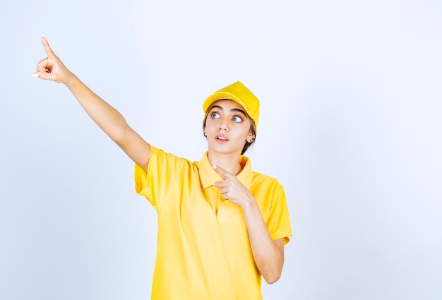 Leveringsvrouw in geel uniform staand en naar boven gericht.