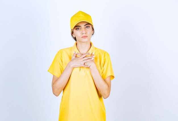 Leveringsvrouw in geel uniform staat en kijkt serieus naar de camera.