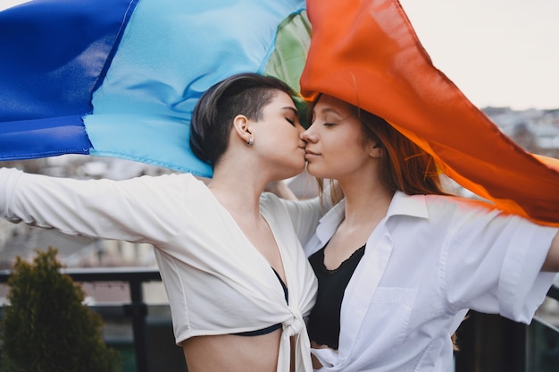 LGBT-vlag in de buurt van meisjes. Meisjes met een niet-traditionele oriëntatie. Knuffels van lesbiennes.