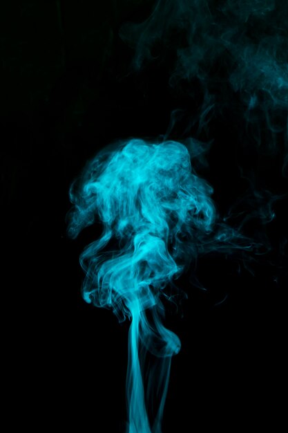 Lichtblauwe rook die tegen zwarte achtergrond blaast