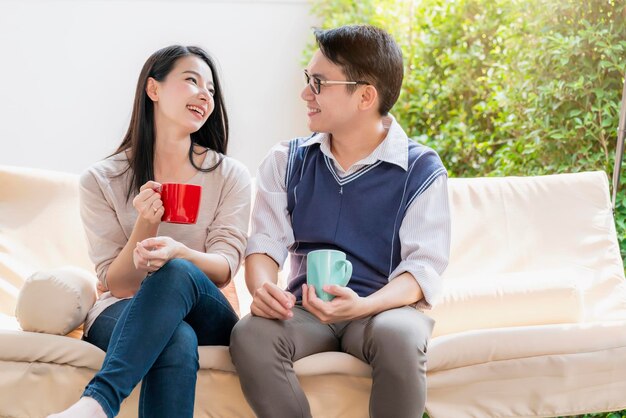 Lief en liefdevol aziatisch stel man en vrouw met warme drank praten samen met geluk en een vredige interieurachtergrond