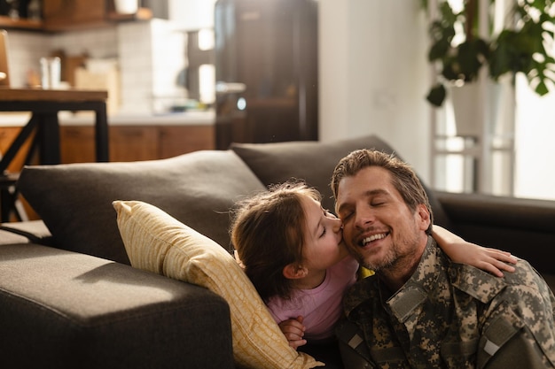 Lief klein meisje kust haar militaire vader in de woonkamer