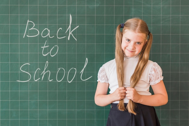 Lief klein meisje permanent in de buurt van schoolbord