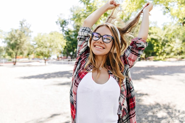 Lief meisje met een bril die lacht met gesloten ogen in het park mooie blanke dame die echte positieve emoties uitdrukt in de zomerdag