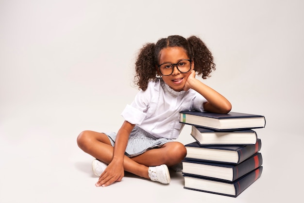 Lief meisje zit naast stapel boeken