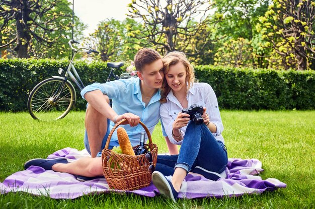 Liefdevolle jong koppel fotograferen en ontspannen op een picknick in een park.