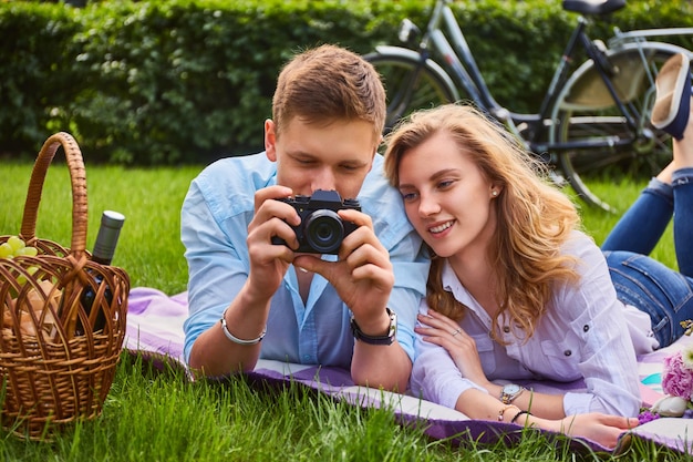 Liefdevolle jong koppel fotograferen en ontspannen op een picknick in een park.