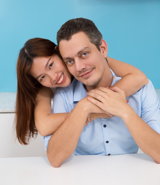 Liefdevolle jonge Aziatische vrouw omarmende echtgenoot
