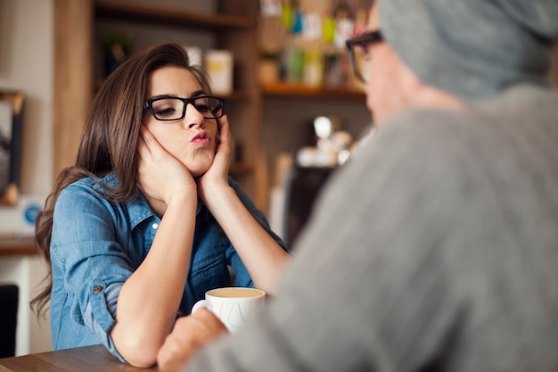 Liefdevolle vrouw kussen blazen naar haar vriendje in café