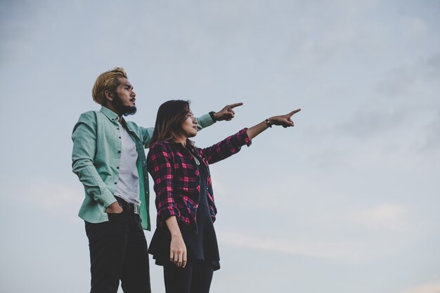 Liefhebbende hipsterpaar staande tegen duidelijke lucht. Paar ontspannend vakantie concept.