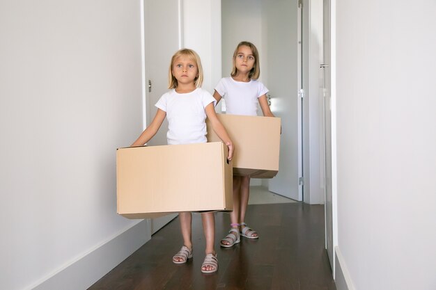 Lieve mooie meisjes verhuizen in een nieuwe flat, met kartonnen dozen in de gang