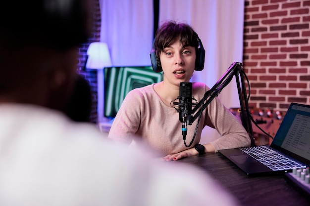 Lifestyle blogger in gesprek met vrouwelijke gast, podcast opnemen met geluidsapparatuur. Influencer in gesprek met vrolijke vrouw om live discussie uit te zenden om op te nemen in studio.