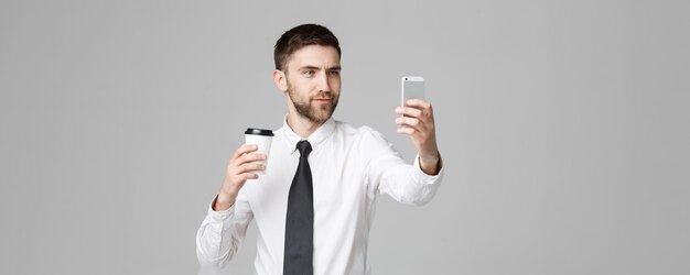 Lifestyle en Business Concept Portret van een knappe zakenman geniet van het nemen van een selfie met take-away kopje koffie Geïsoleerde witte achtergrond Copy Space