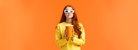 Gratis foto lifestyle hobby en mensen concept schattige geeky roodharige vrouw in d papieren bril met popcorn en b