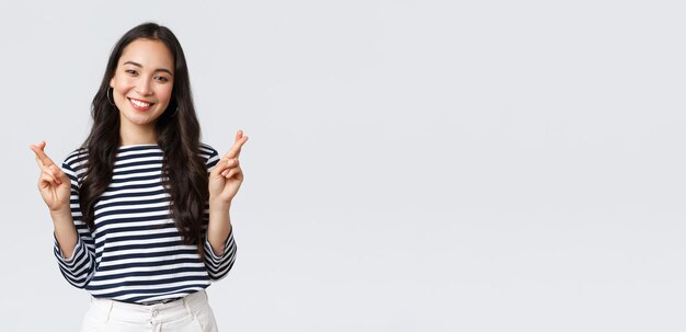Lifestyle mensen emoties en casual concept Hoopvol opgewonden schattige Koreaanse vrouw die wens doet met gekruiste vingers glimlachend anticiperend op positief nieuws smeken droom die uitkomt