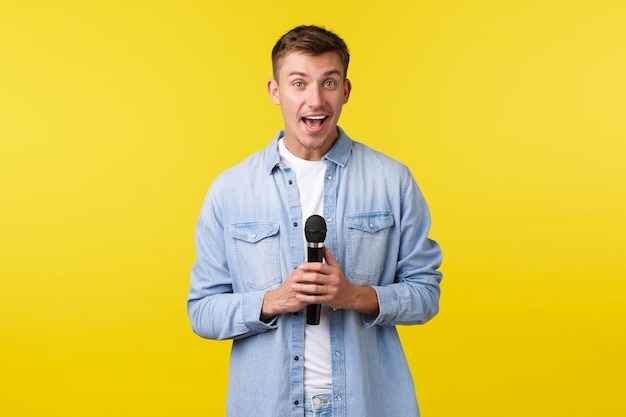 Lifestyle, mensen emoties en zomer vrije tijd concept. Levendige, knappe blonde man die wegkijkt en glimlacht, op het podium praat, stand-up uitvoert of karaoke zingt met microfoon.