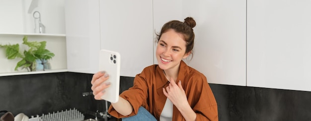 Gratis foto lifestyle shot van een jonge vrouw die videochat met behulp van een smartphone-app om online te praten