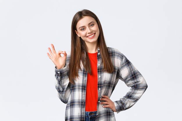 Lifestyle, verschillende emoties, vrijetijdsactiviteiten concept. Zelfverzekerde mooie jonge vrouw zegt geen probleem, garandeert kwaliteit, toont goed teken, kantelt het hoofd en glimlacht tevreden, tevreden goed resultaat
