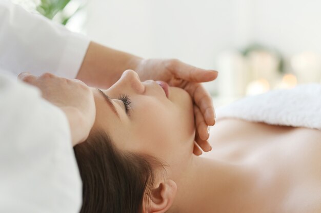 Liggende vrouw die een massage ontvangt. Craniosacraal therapie