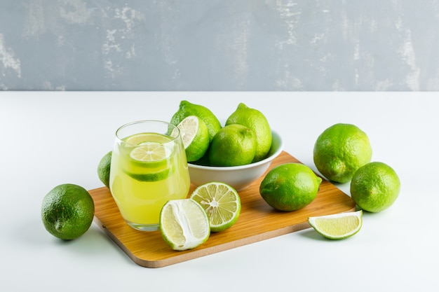 Limonade in een glas met citroenen, snijplank hoge hoek uitzicht op wit en gips