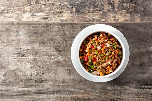 Linzensalade met peppersonion en wortel in een kom op houten tafel