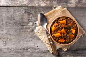 Gratis foto linzenstoofpot ragout met pompoen en wortel in kom op houten tafel