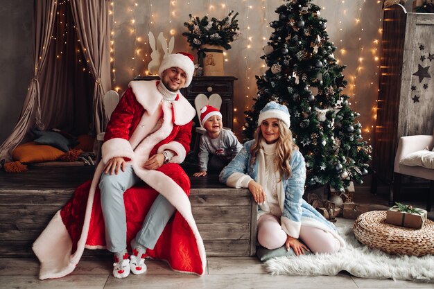 Little Santa, Father Frost en Snow Maiden lachend in xmas interieur met versierde kerstboom.