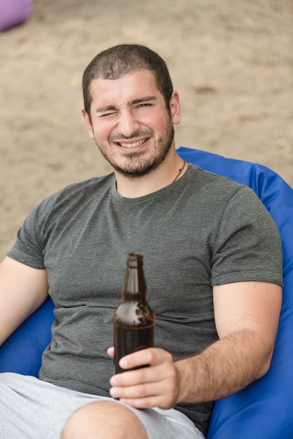 Gratis foto loensende man met bier op het strand