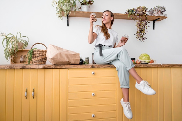 Gratis foto long shot vrouw poseren op een aanrecht in de keuken