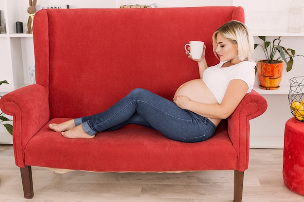 Gratis foto long shot zwangere vrouw zittend op de bank