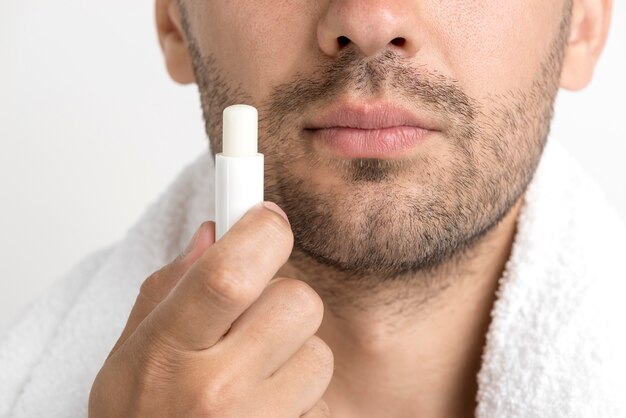 Lose-up van man met handdoek om zijn nek met lippenbalsem