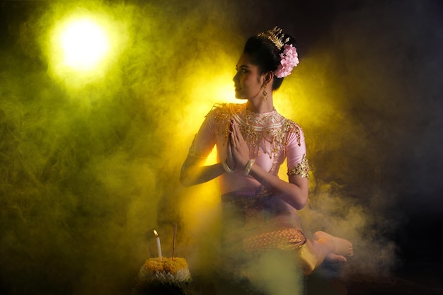 Loykrathong-jurk van thaise traditionele klederdracht of zuidoost-azië gouden jurk in aziatische vrouw met decoratiestandaard express blije glimlach voor loy krathong drijvend festival op zwarte achtergrond