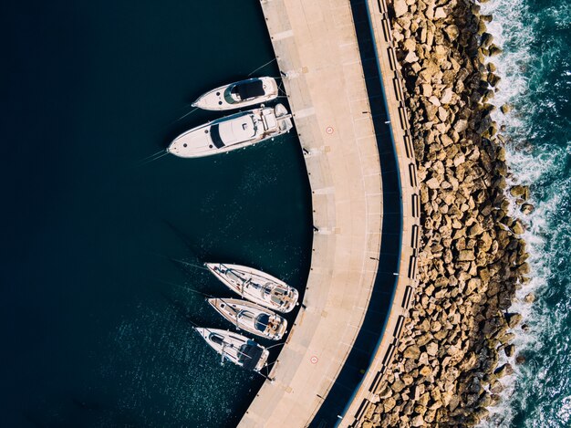 Luchtfoto boven schot van witte zeilboten aangemeerd aan de kust van de oceaan