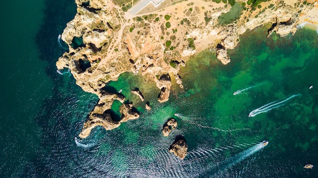 Gratis foto luchtfoto bovenaanzicht van schilderachtige ponta da piedade van lagos, portugal. ruige kliffen aan zee en aqua oceaanwater in de algarve in portugal