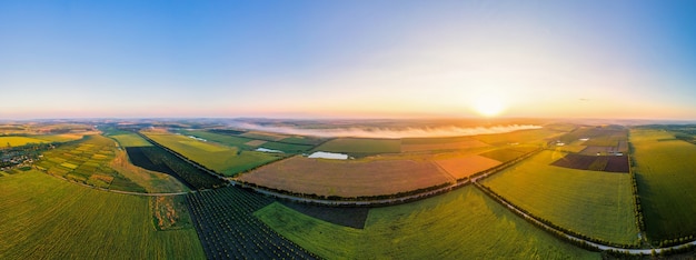 Luchtfoto drone panorama uitzicht op de natuur in Moldavië bij zonsondergang. Rook van een vuur, brede velden, weg, zon